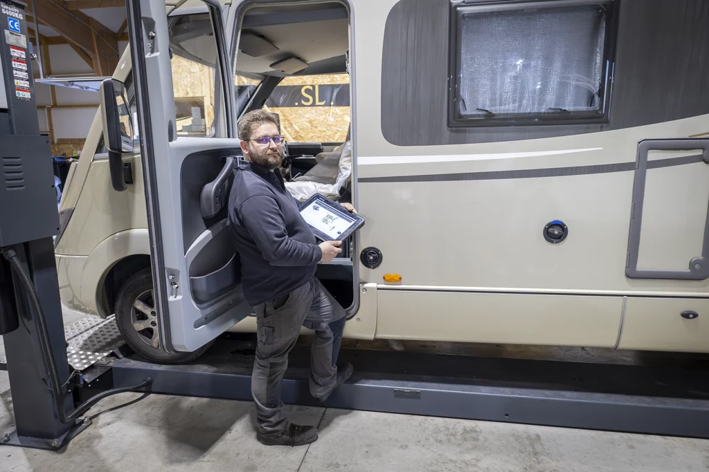 technicien réalisant un diagnostic sur un camping-car avec tablette