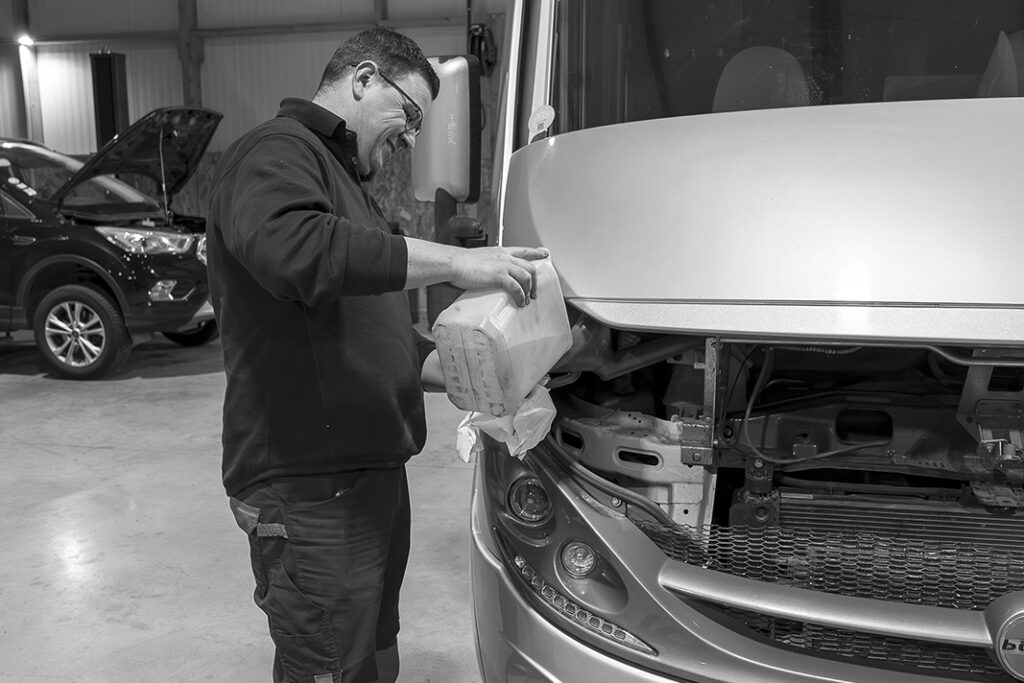 mécanicien faisant le niveau d’un véhicule dans un garage automobile