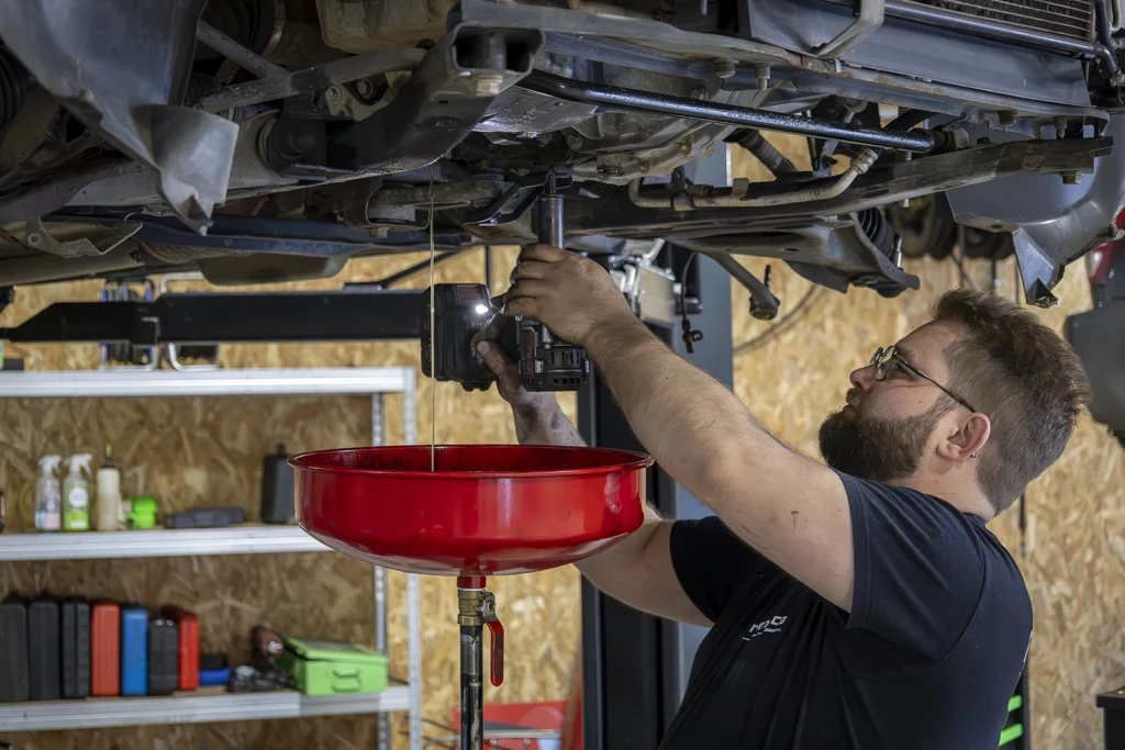 vidange moteur avec récupération d’huile sous un véhicule